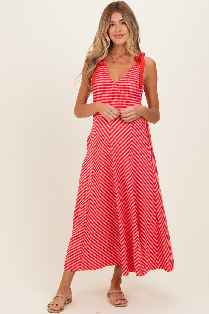 woman wearing a red and white striped maternity dress with a v-neckline and adjustable straps, showing her baby bump