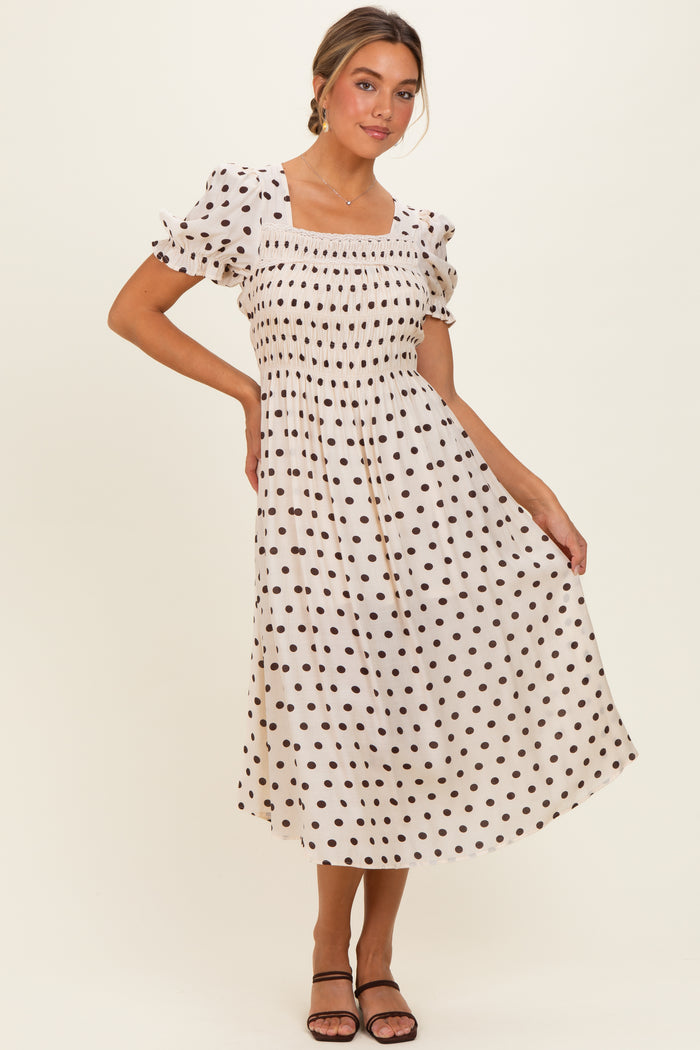 woman wearing a cream polka dot midi dress with puff sleeves and a smocked bodice