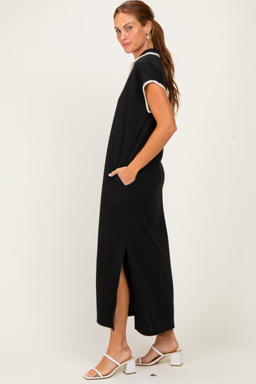 woman wearing a black maxi dress with short sleeves and side slits, featuring a white trim detail and pockets