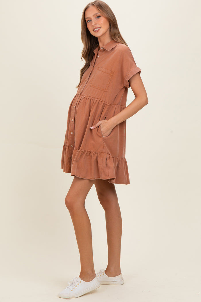 woman wearing a rust-colored maternity shirt dress with a ruffled hem and pockets, showing her baby bump