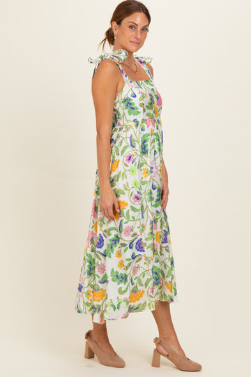 woman wearing a floral print midi dress with tie straps and a smocked bodice, paired with beige heels