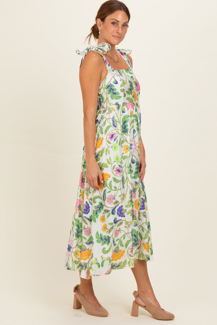 woman wearing a floral print midi dress with tie straps and a smocked bodice, paired with beige heels