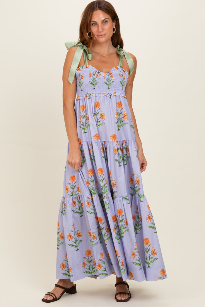 woman wearing a lavender floral maxi dress with smocked bodice and green bow straps