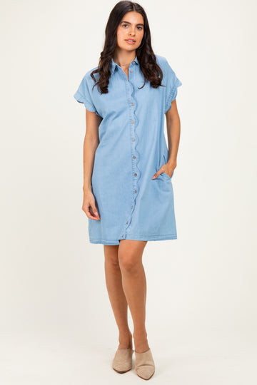 woman wearing a light blue denim shirt dress with buttons and short sleeves, standing with hands in pockets