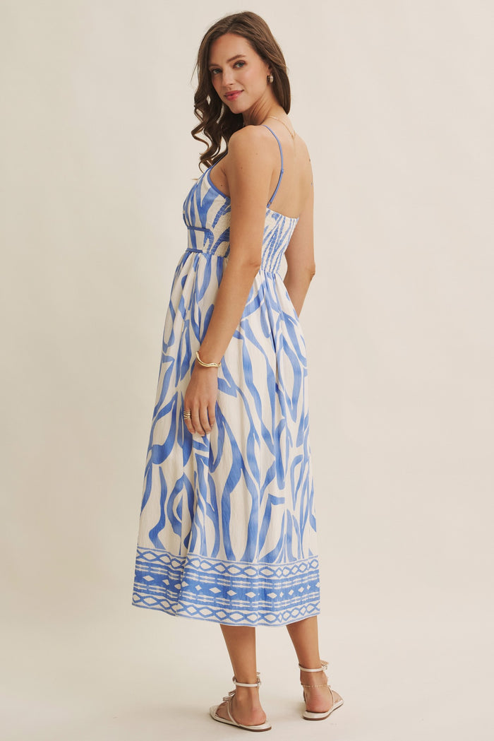 woman wearing a blue and white patterned maxi dress with adjustable straps and a flowing skirt