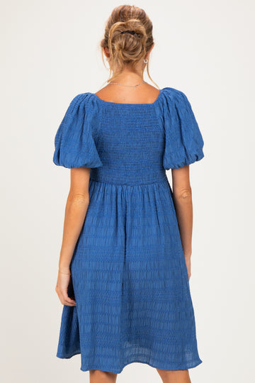 woman wearing a blue smocked back maternity dress with puff sleeves
