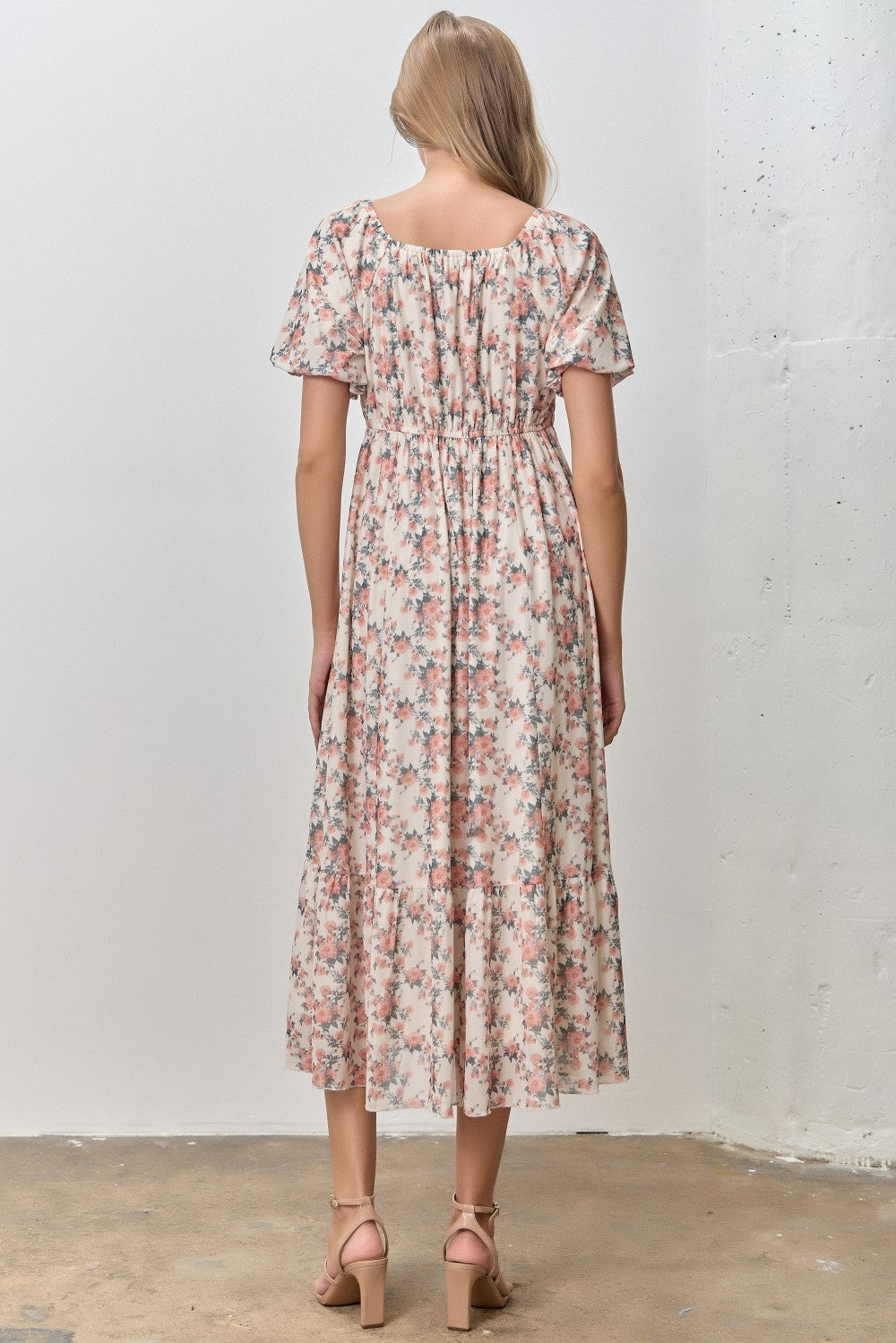 woman wearing a floral midi dress with short sleeves and a gathered waist, seen from the back
