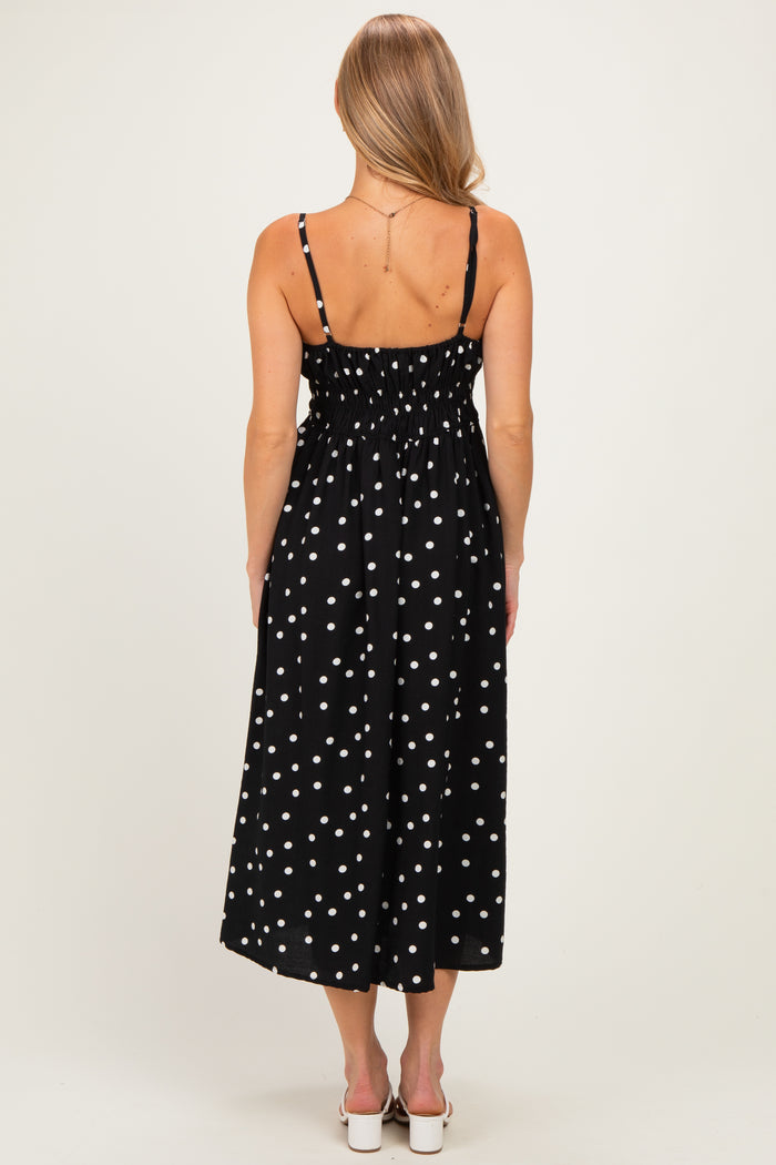 woman wearing a black midi dress with white polka dots and smocked back detail, shown from the back