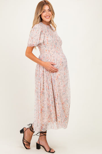 woman wearing a floral patterned maternity dress with a gathered waist and short sleeves, holding her baby bump