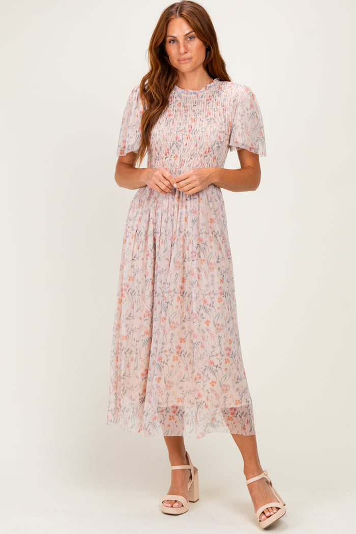 woman wearing a light pink floral midi dress with puff sleeves and a smocked bodice, standing in stylish heels