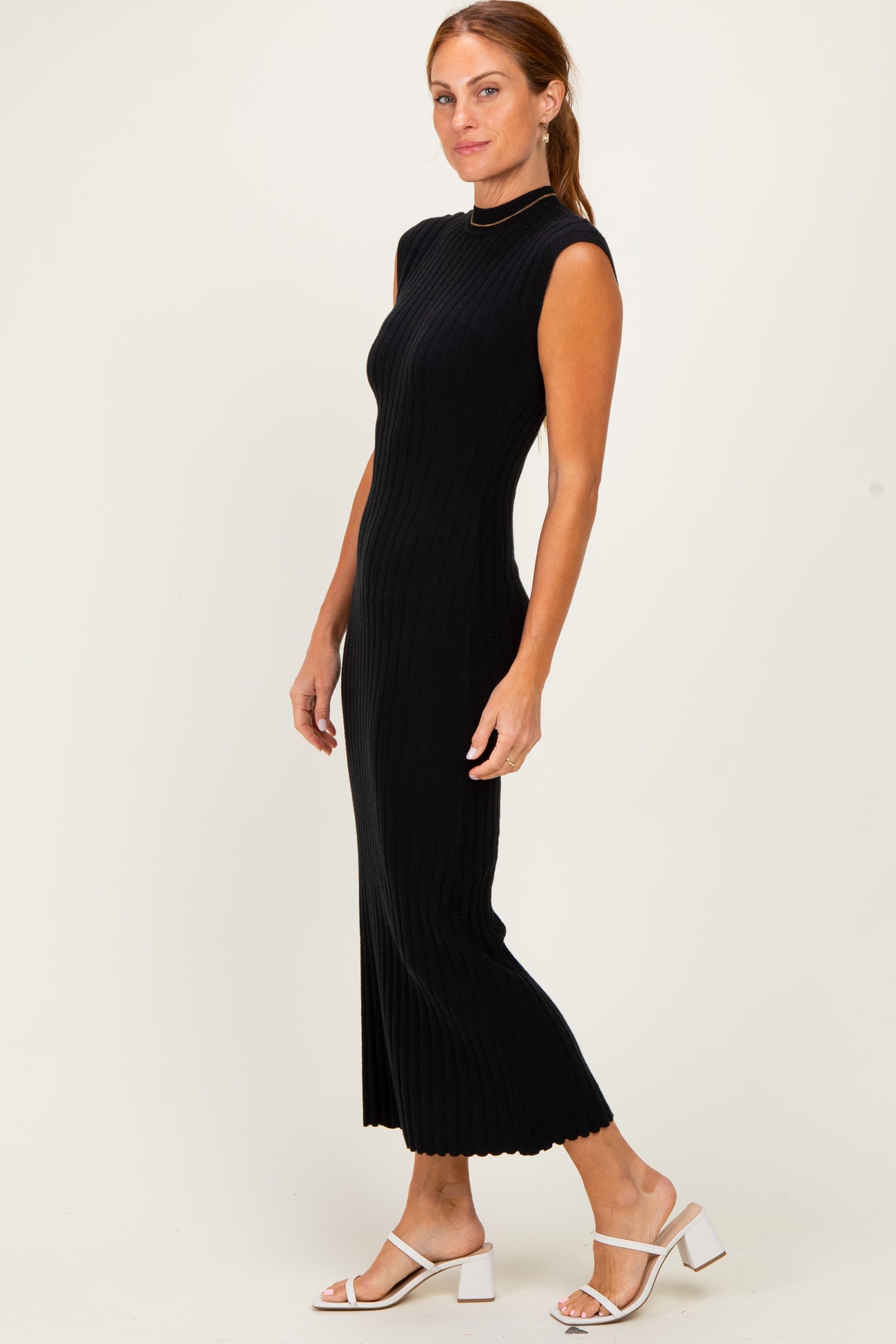 woman wearing a black ribbed sleeveless midi dress and white heeled sandals