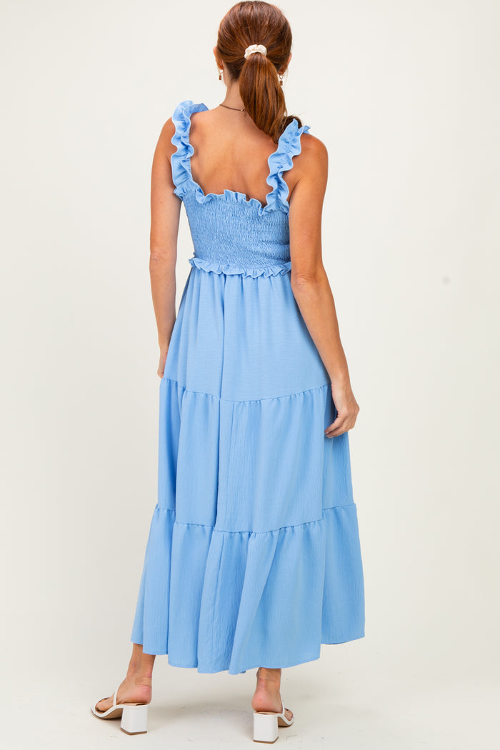 woman wearing a light blue smocked maxi dress with ruffled straps and tiered hem, viewed from the back