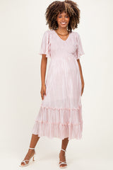woman wearing a light pink maternity dress with short flutter sleeves and ruffle hem, showcasing her baby bump