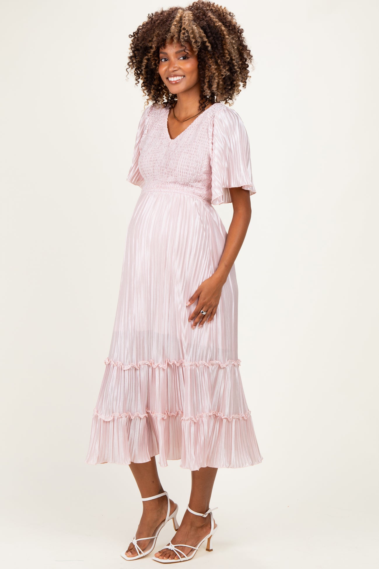 woman wearing a pink striped maternity dress with short sleeves and ruffle hem, highlighting her baby bump