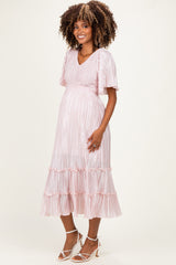 woman wearing a pink striped maternity dress with short sleeves and ruffle hem, highlighting her baby bump