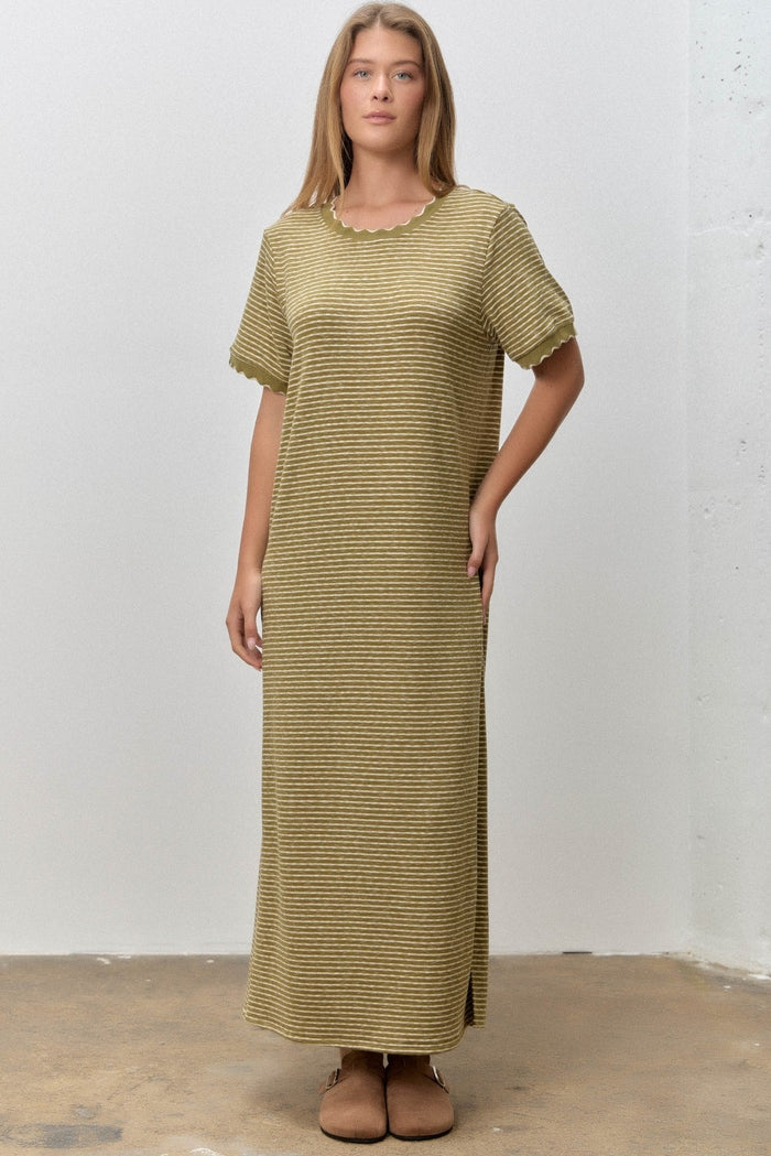 woman wearing a light olive green striped maxi dress with short sleeves and a scalloped neckline