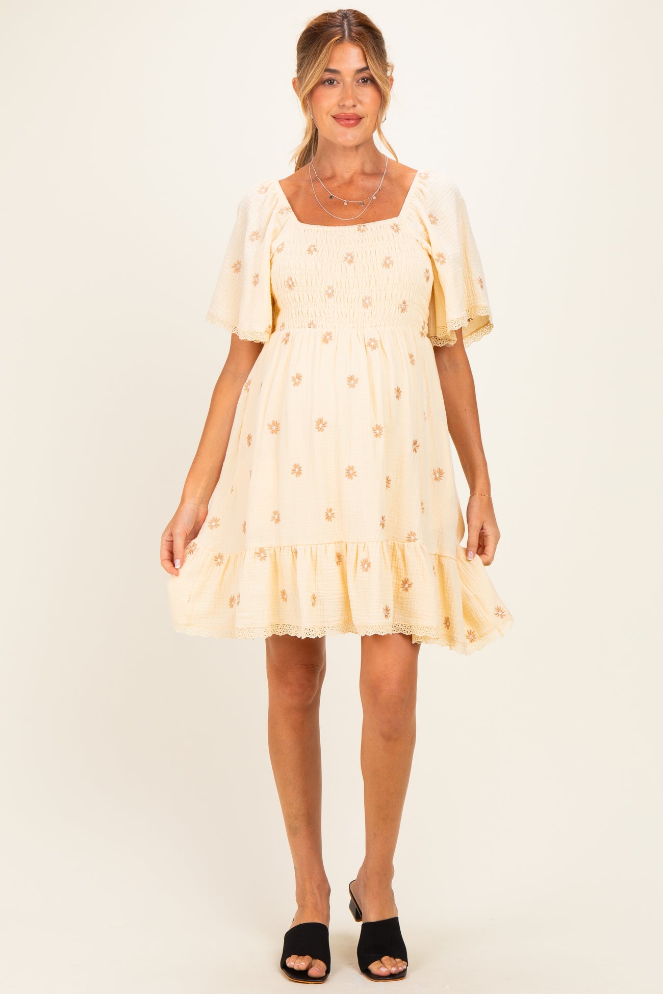 woman wearing a cream floral maternity dress with puff sleeves and ruffled hem