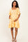 woman wearing a yellow maternity dress with floral embroidery and a tiered hem, holding her baby bump