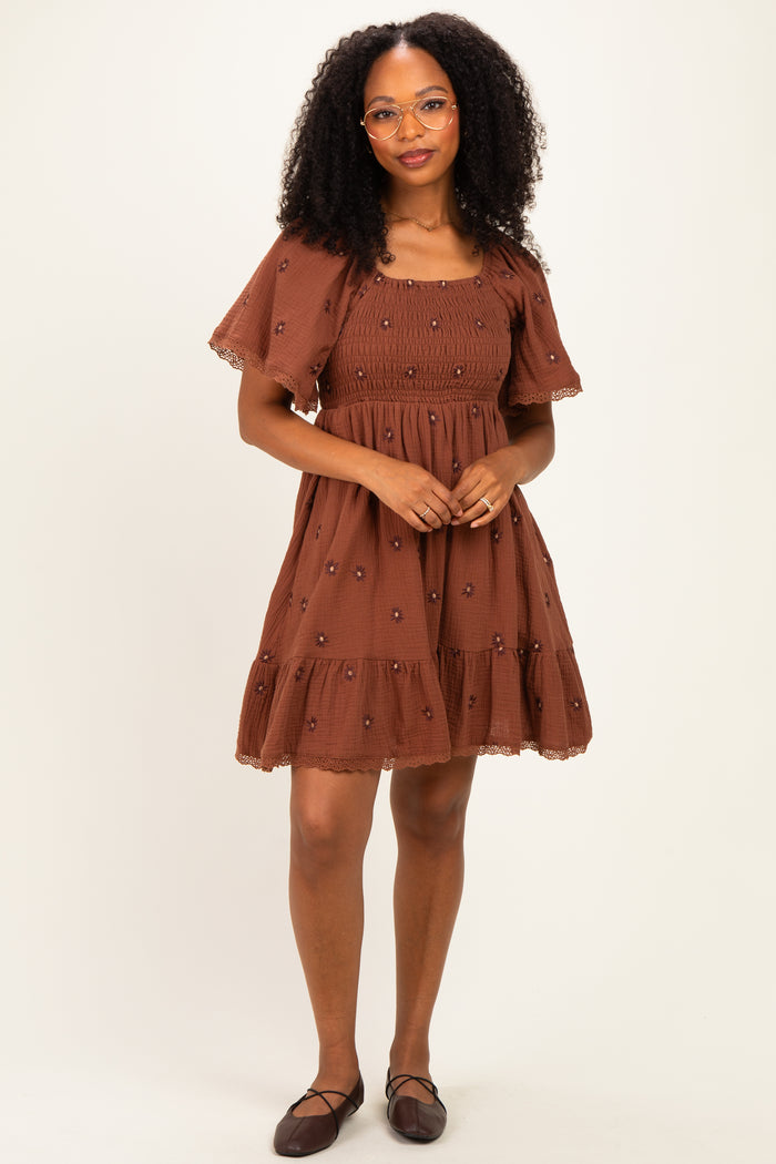 woman wearing a brown embroidered short dress with puff sleeves and a tiered skirt