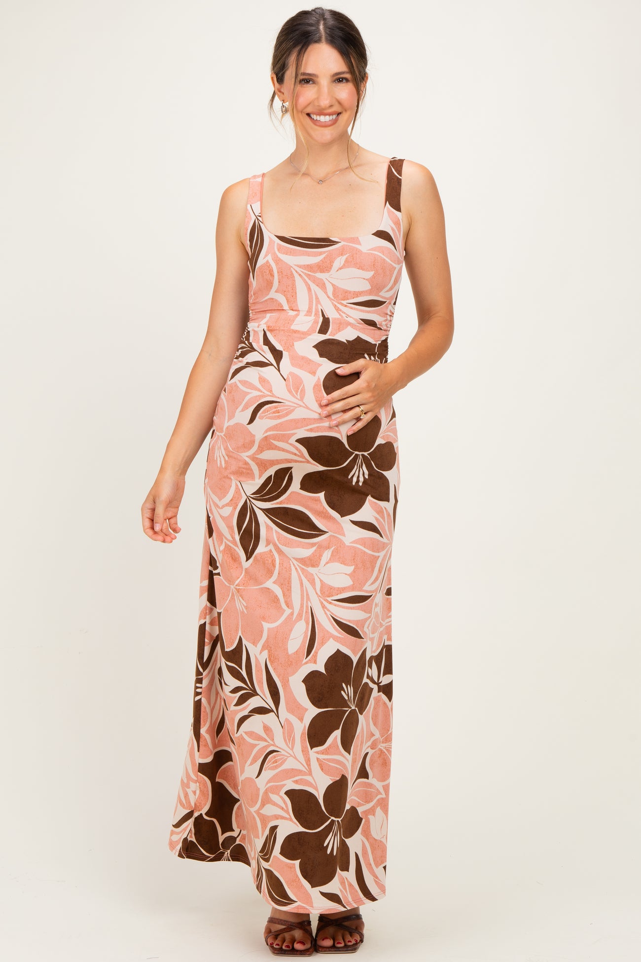 woman wearing a floral print maternity maxi dress with a fitted bodice and a flowing skirt, holding her baby bump