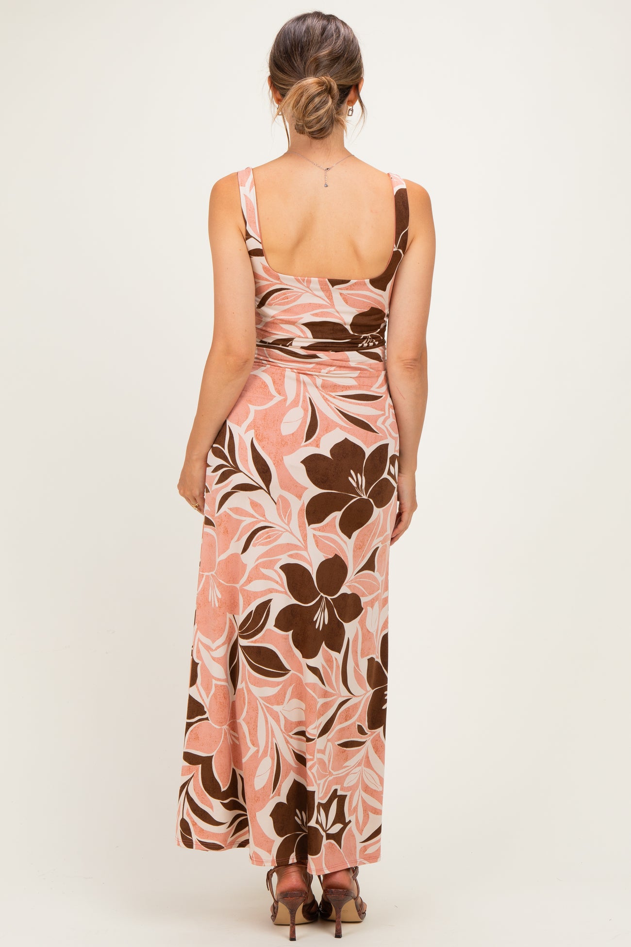 woman wearing a pink floral print maternity maxi dress, showing the back view with a fitted silhouette