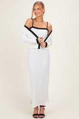 woman wearing a white ribbed maxi dress with a black cardigan, styled with black strappy heels and a simple necklace
