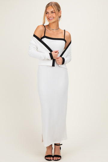 woman wearing a white ribbed maxi dress with a black cardigan, styled with black strappy heels and a simple necklace