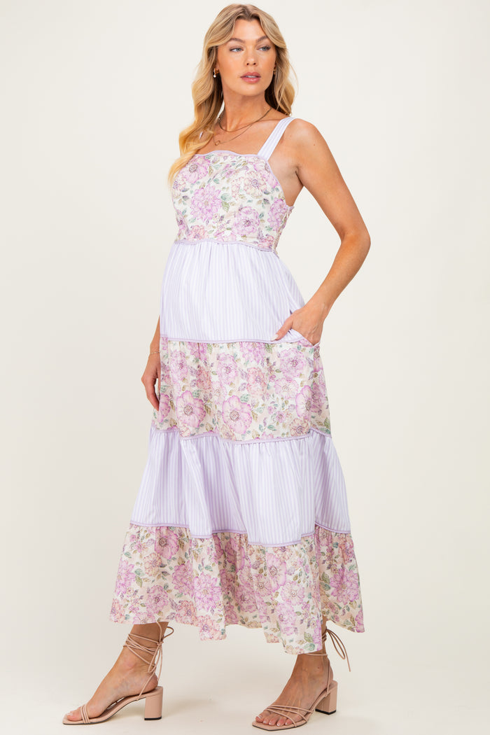 woman wearing a floral and striped maternity maxi dress with pockets and showing her baby bump
