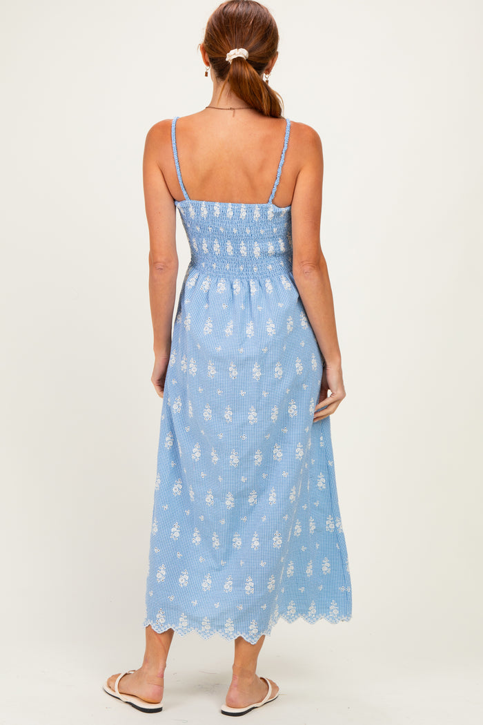 woman wearing a light blue maxi dress with a smocked bodice and white floral embroidery, viewed from the back