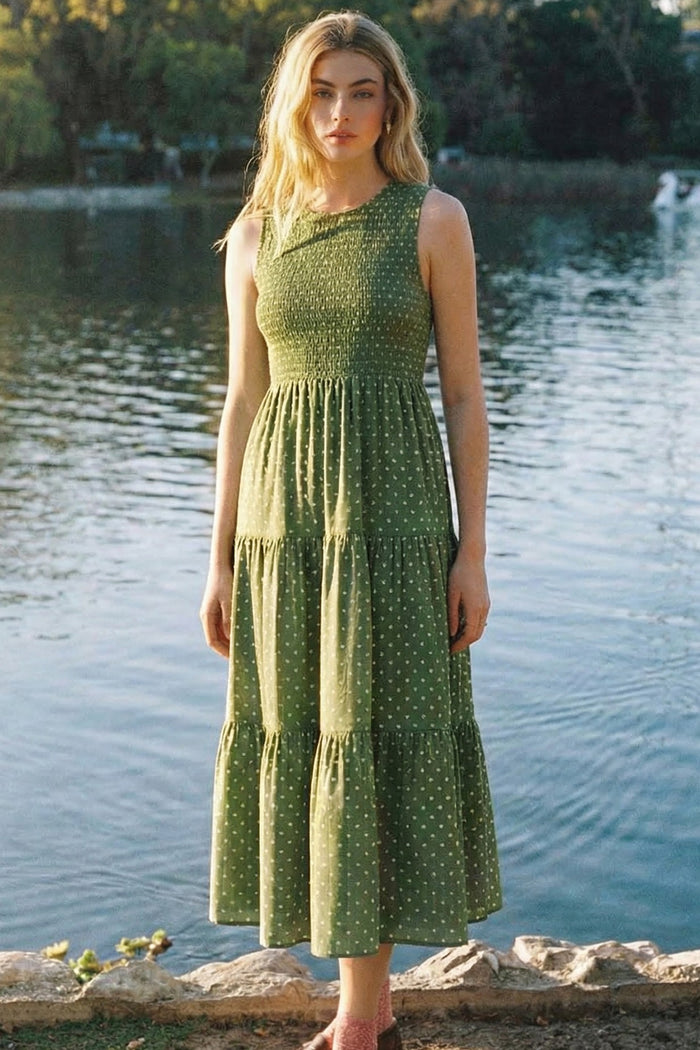 woman wearing a green polka dot tiered midi dress posed by a lake