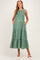 woman wearing a green polka dot maternity dress with smocking and tiers, featuring pockets and a flowing silhouette