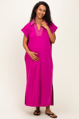 woman wearing a hot pink maternity maxi dress with a collar and side slits, gently cradling her baby bump