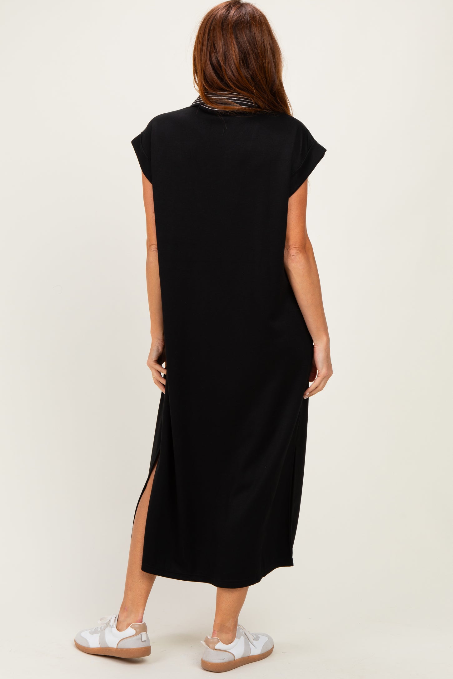 woman wearing a black cap sleeve maxi dress with side slits and styled with white sneakers