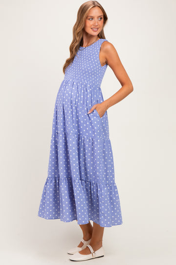 woman wearing a light blue polka dot maternity maxi dress with a smocked bodice and pockets, showcasing her baby bump