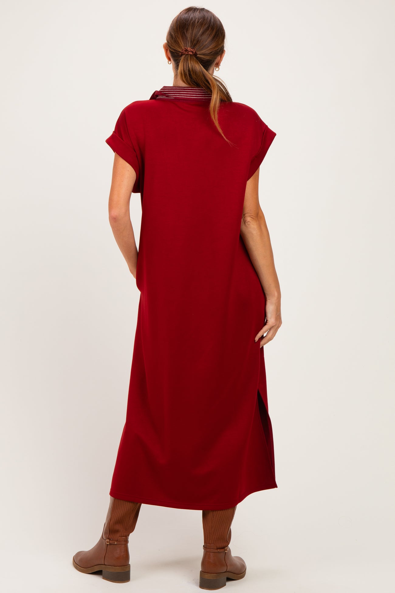 woman wearing a ruby red short sleeve dress with side slits and brown knee-high boots