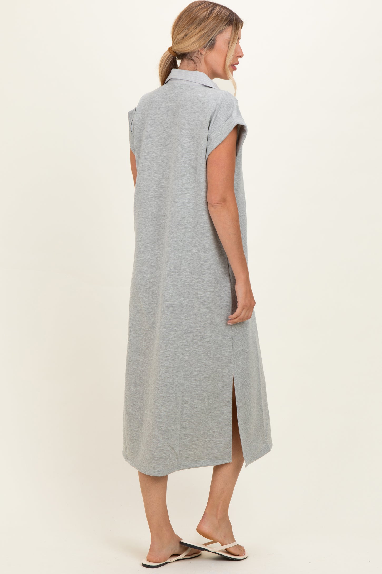 woman wearing a gray maxi dress with short sleeves and side slits, seen from the back