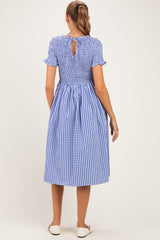 woman wearing a blue and white gingham maternity dress with short sleeves and a keyhole back detail