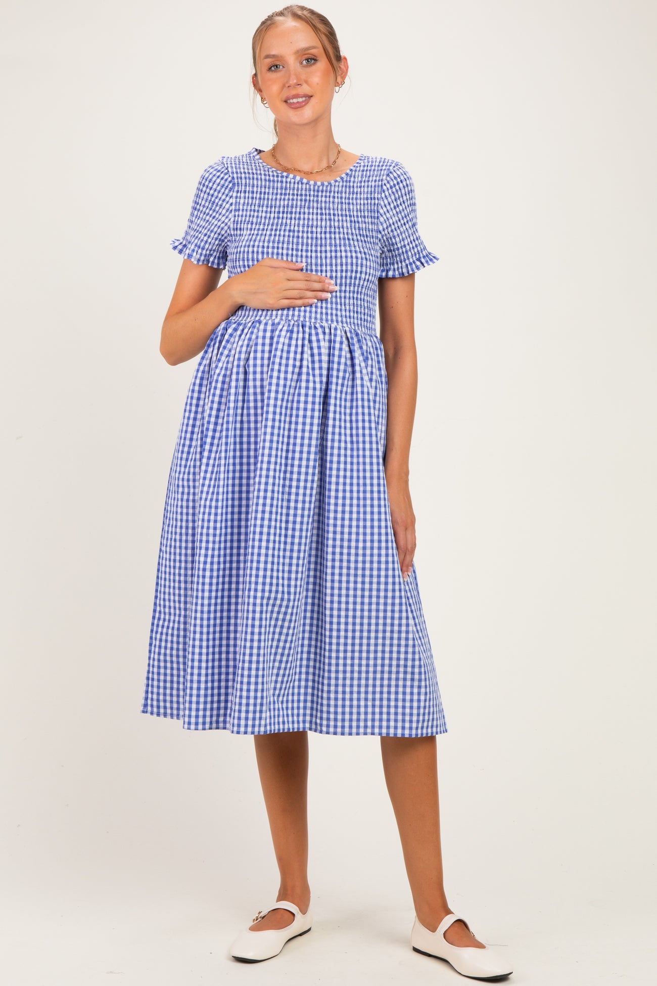 woman wearing a blue and white gingham maternity dress with short sleeves and a baby bump