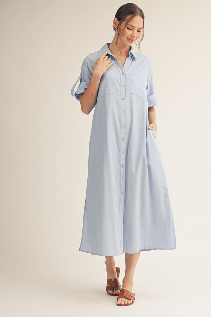 woman wearing a light blue button-up shirt dress with rolled sleeves and a relaxed fit