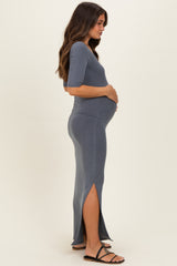 woman wearing a gray ribbed maternity dress with side slits and holding her baby bump
