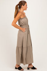 woman wearing a taupe off-the-shoulder maxi dress with a drawstring waist and side pockets