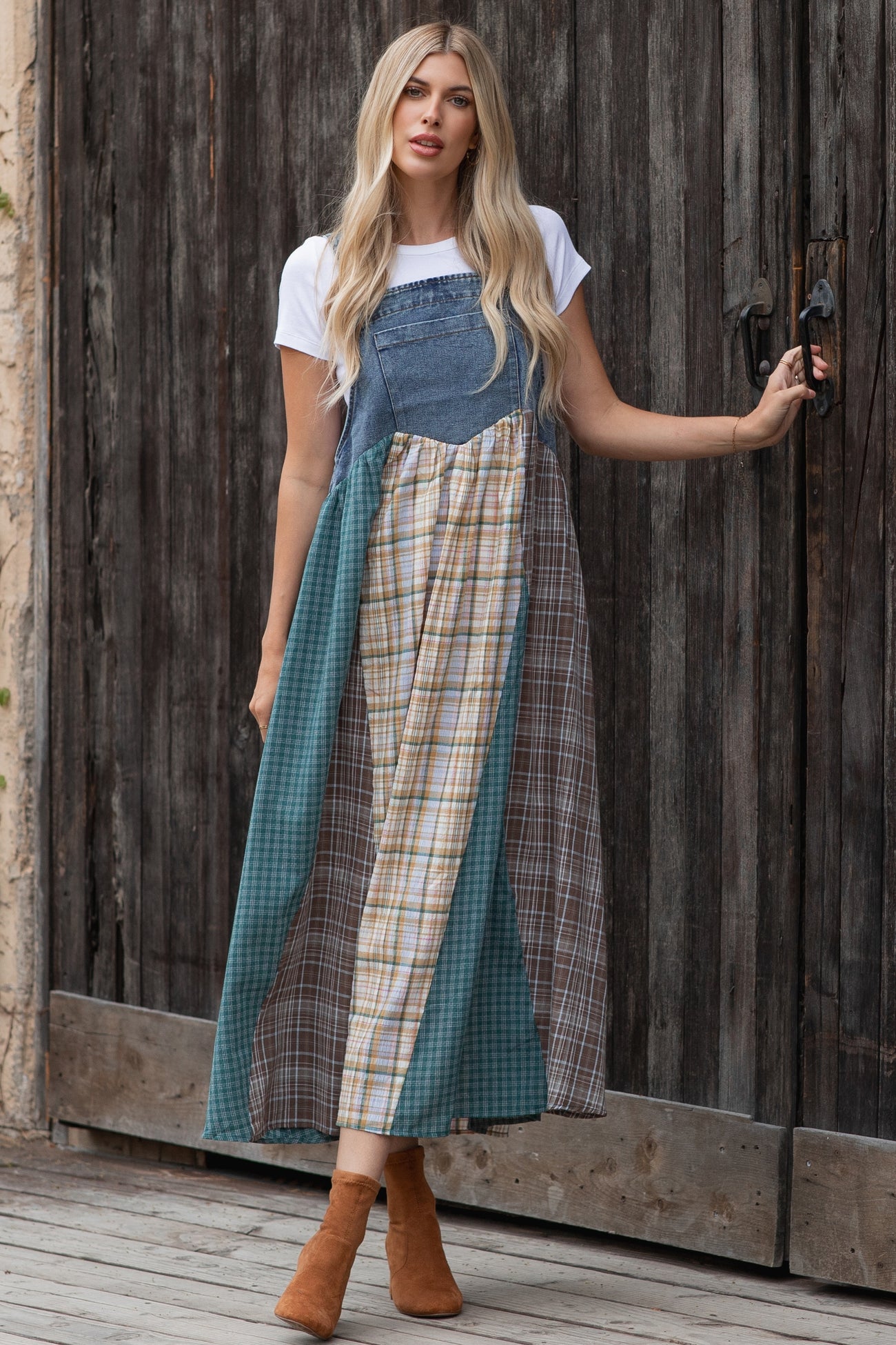 woman wearing a denim patchwork maxi dress with plaid and solid panels, paired with brown ankle boots