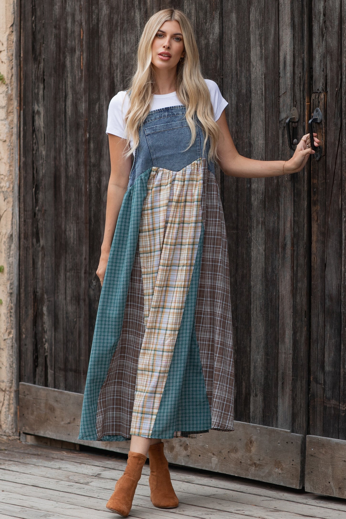 woman wearing a denim patchwork maxi dress with plaid and solid panels, paired with brown ankle boots