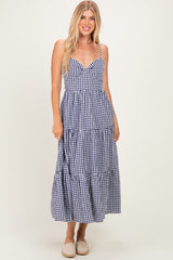 woman wearing a navy and white gingham print tiered maxi dress with spaghetti straps and a sweetheart neckline