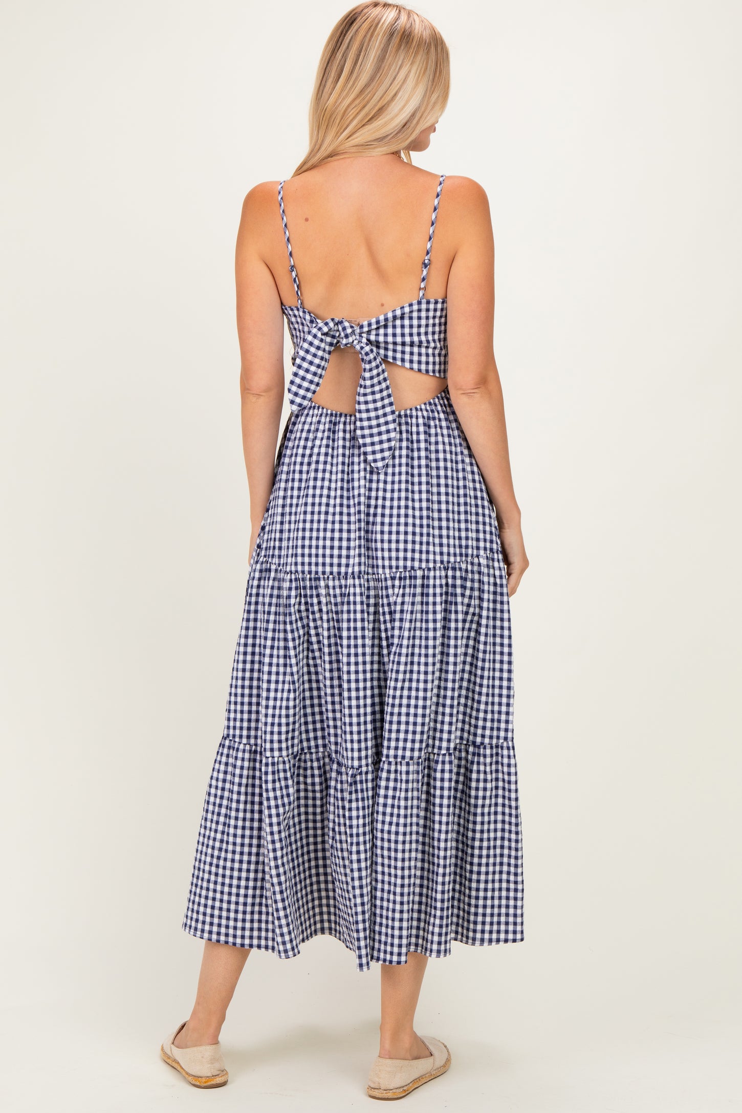 woman wearing a navy and white checkered maxi dress with a bow detail and an open back