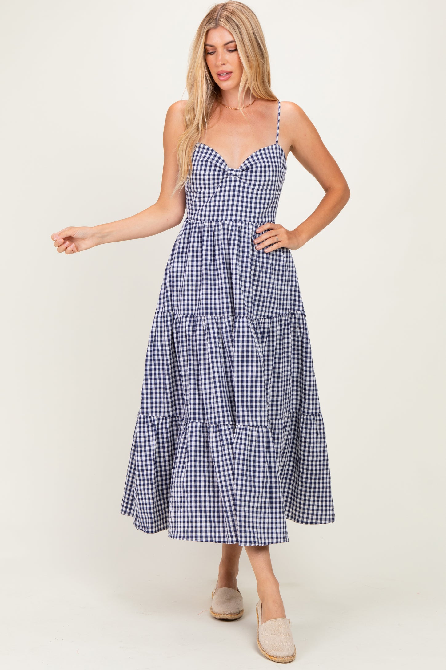 woman wearing a navy and white gingham tiered maxi dress with spaghetti straps and a sweetheart neckline
