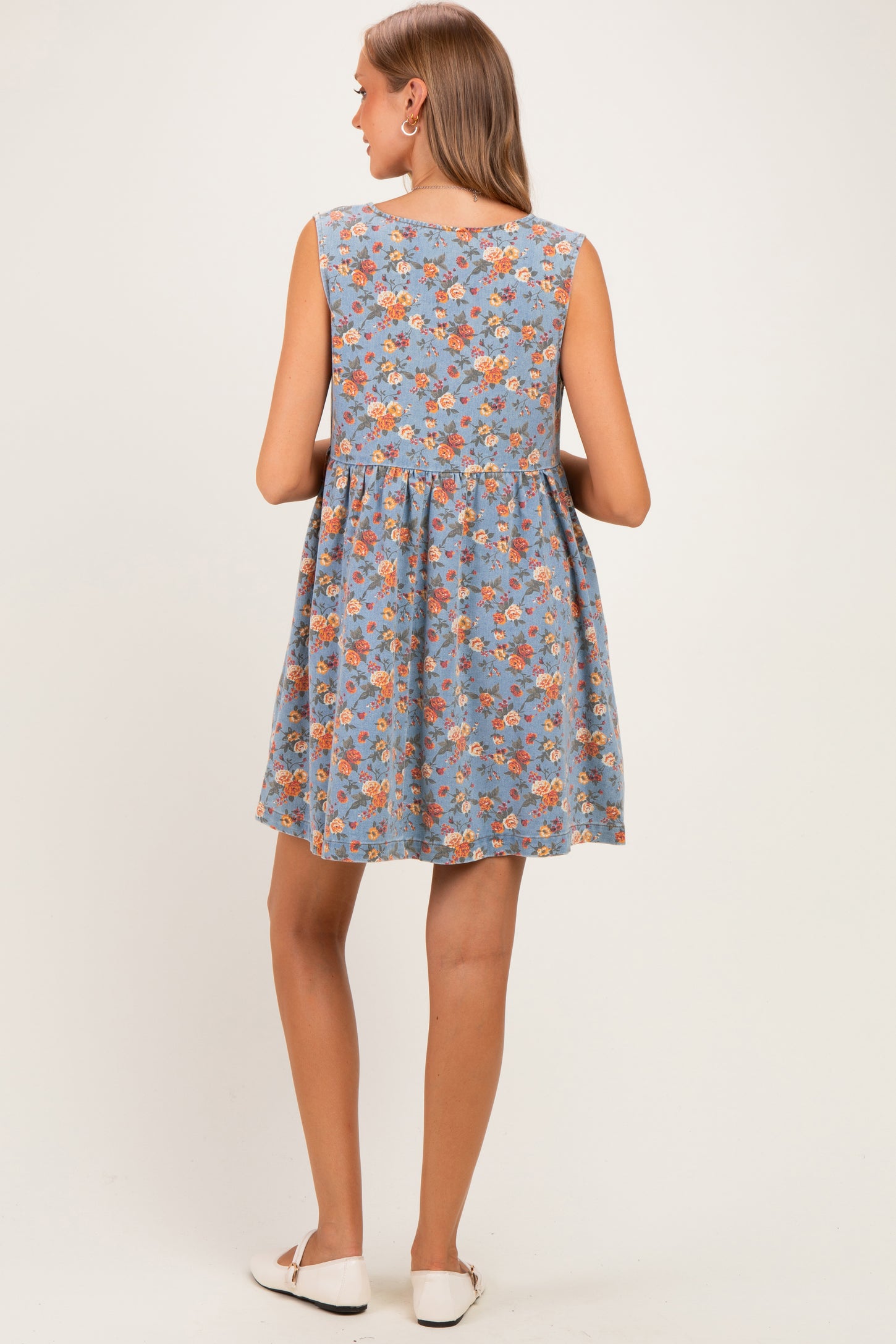 woman wearing a blue floral maternity dress with a flowy, A-line silhouette and sleeveless design, showing her back