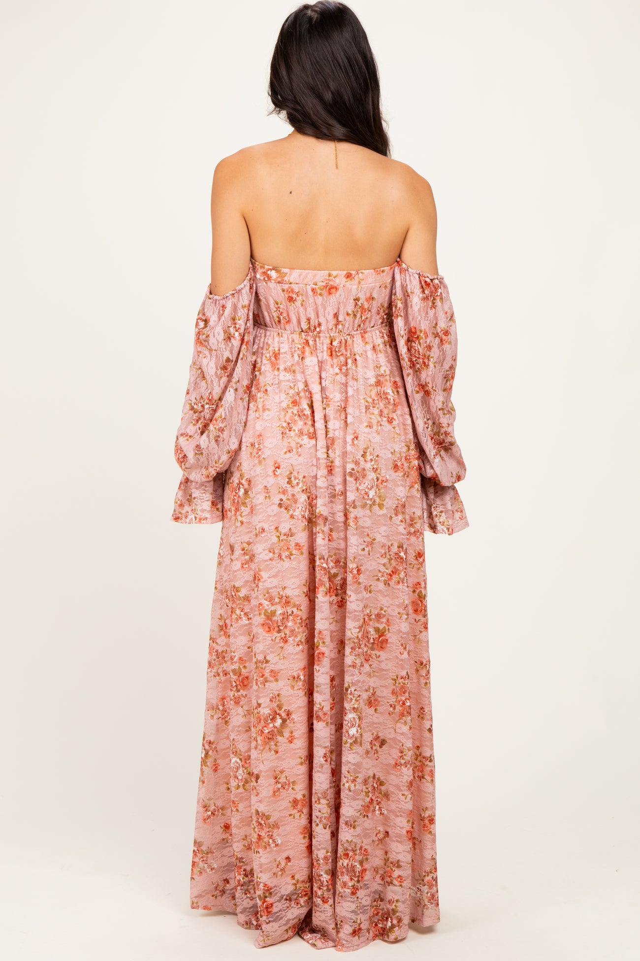 woman wearing a pink off-the-shoulder maxi dress with floral print and long puff sleeves, shown from the back