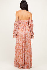 woman wearing a pink off-the-shoulder maxi dress with floral print and long puff sleeves, shown from the back
