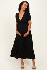woman wearing a black maternity dress with a deep v-neck and an elastic waist, holding her baby bump